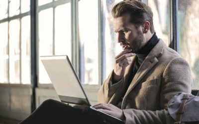 man holding his chin facing laptop computer