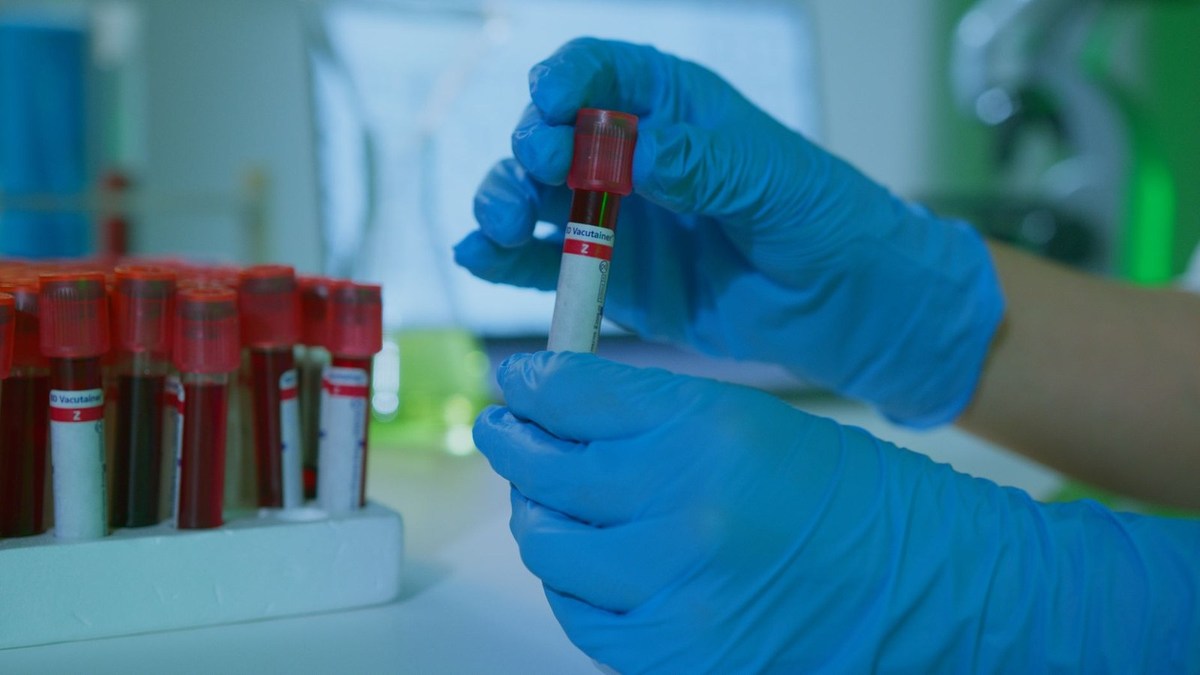 Scientifique examinant un tube à essai rouge dans un environnement de laboratoire