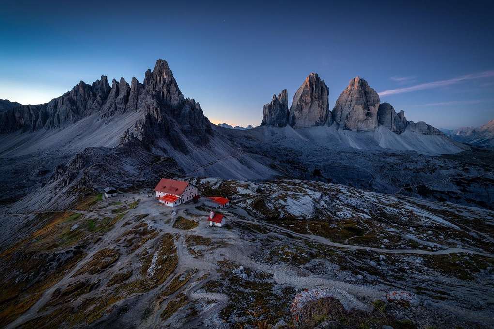 Maison rouge au milieu des montagnes enneigées sous un ciel bleu