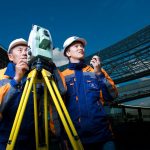 2 men in white hard hat holding a machine